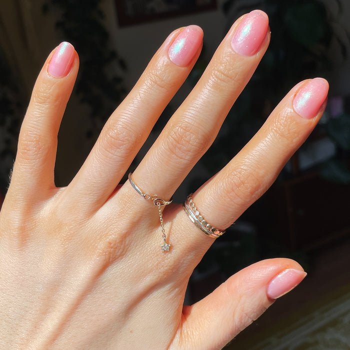 Hand showing shiny pink iridescent manicure using That’s Amoray gel polish in natural light at home