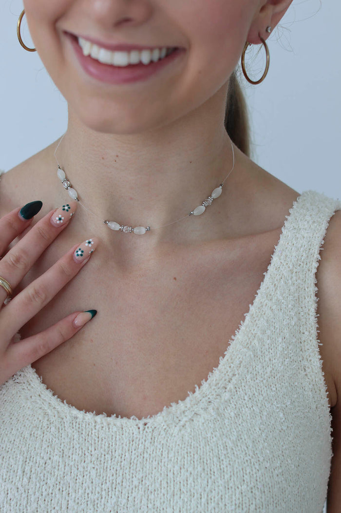 girl poses with a white beaded choker on