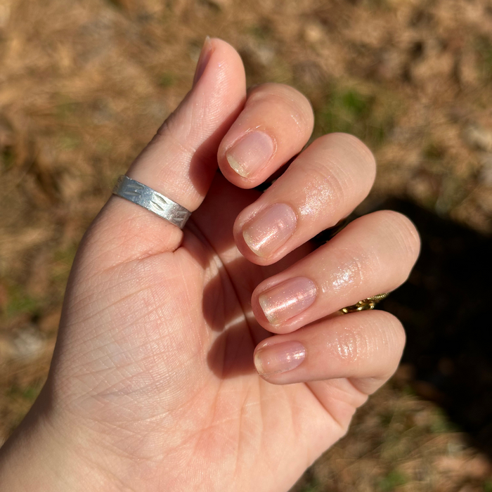 The Golden Effect Top Coat giving natural nails a luminous golden hour glow for a radiant and long-lasting manicure.