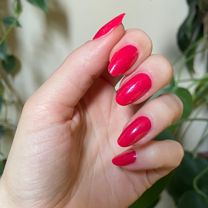 The Sparkle Fairy Effect Top Coat enhancing glossy magenta shimmer on almond-shaped nails for a vibrant manicure look