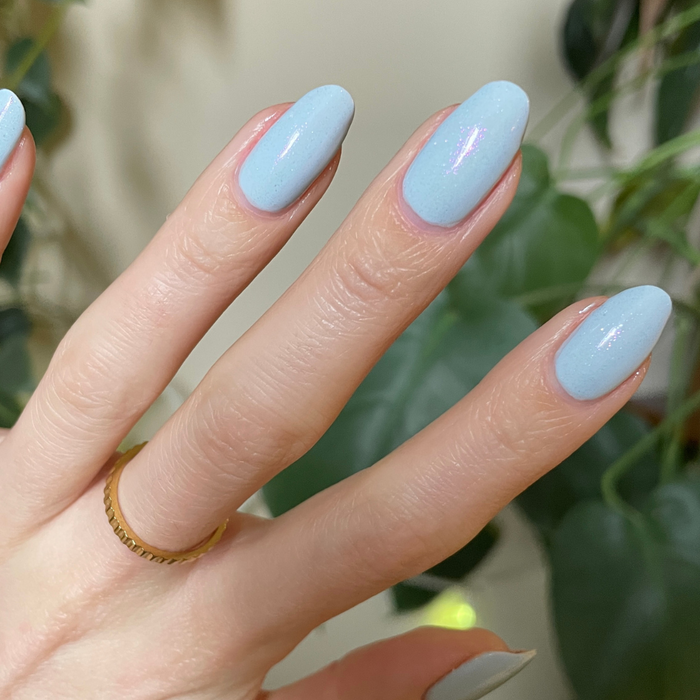 The Sparkle Fairy Effect Top Coat over pastel blue gel polish showing iridescent shimmer on almond-shaped nails for mani