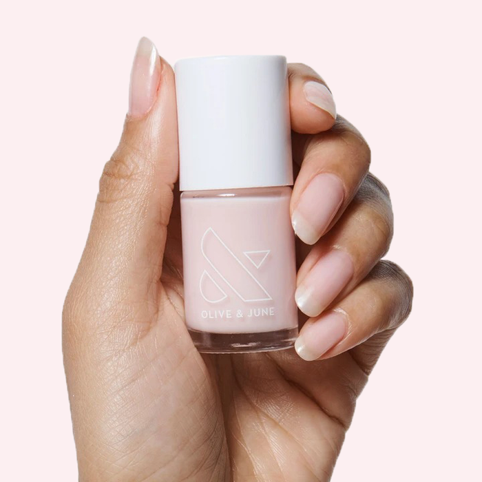 Hand holding a neutral polish bottle from THE STARTER SET with natural nails for an easy at-home mani
