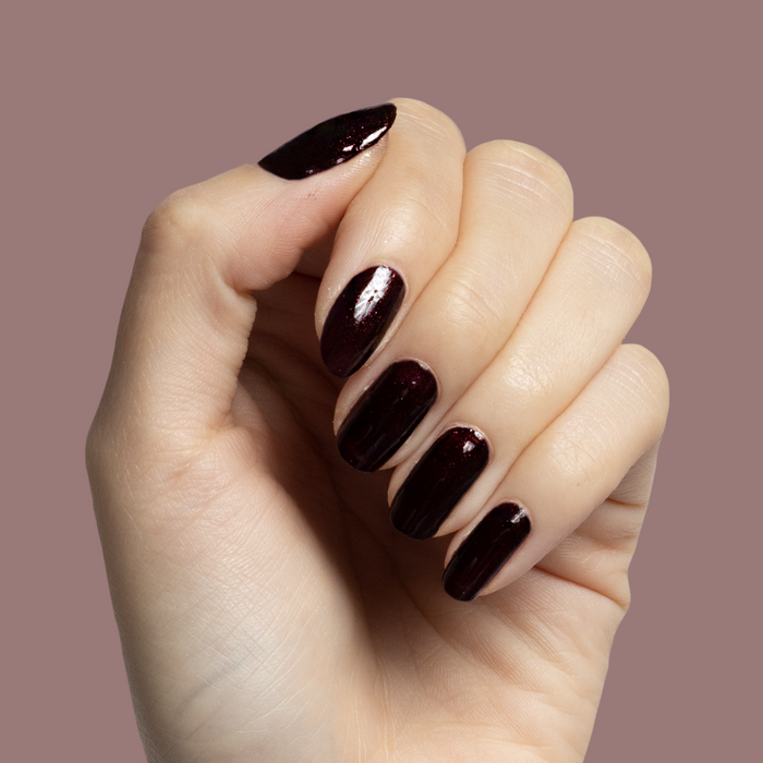 Hand with nails polished in deep plum metallic shimmer shade To Me, You Are Perfect for at-home manicure by Olive and June