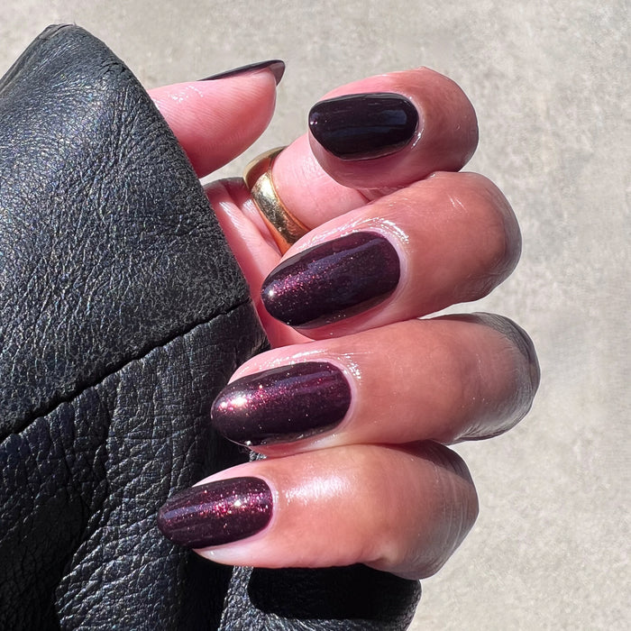 Hand displaying metallic deep plum manicure in To Me, You Are Perfect polish for an easy at-home mani look