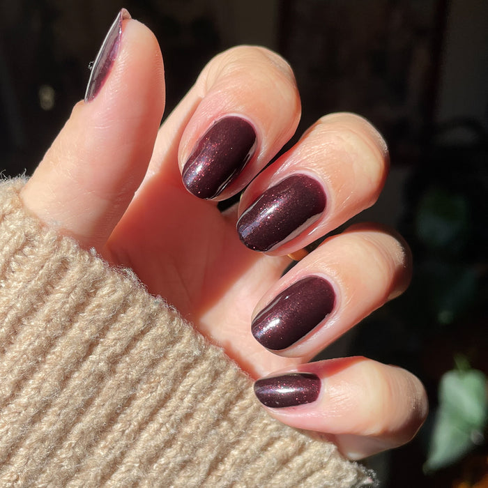 Hand showing nails polished in To Me, You Are Perfect deep plum metallic shimmer gel polish manicure by Olive and June