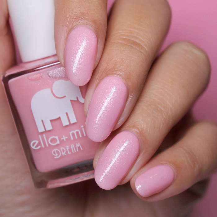 Toes Down Chin Up shimmery pink nail polish close-up with the bottle on a pink background
