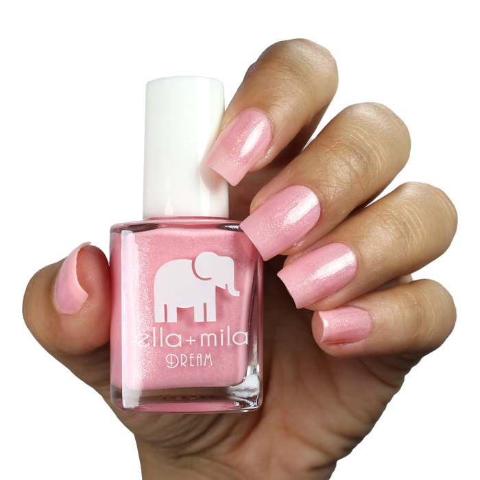 Toes Down Chin Up true pink shimmer nail polish on a medium skin tone, hand holding the bottle