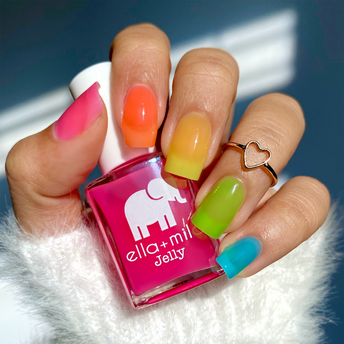 Tooti Fruiti Lover Boy blue with rainbow jelly mix-and-match manicure, holding a pink bottle