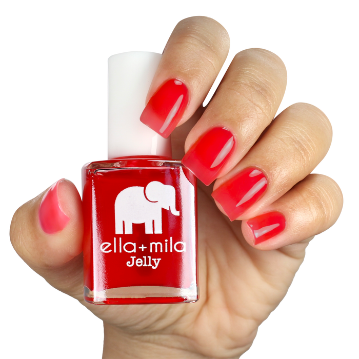 Watermelon Jelly Rancher pink red jelly nail polish on a light skin tone, holding the bottle