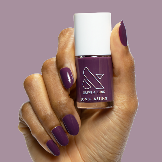 Hand holding Who Likes Raisins? long-lasting polish by Olive and June on matching dark purple almond-shaped nails