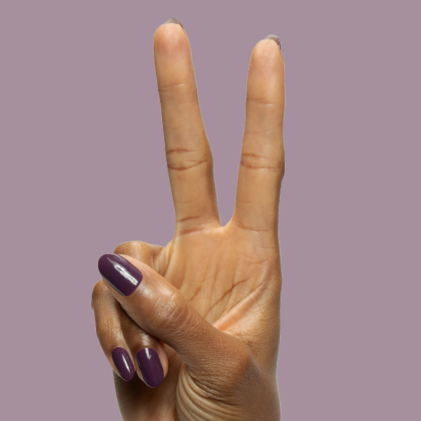 Hand making peace sign with Who Likes Raisins? gel polish on medium rounded nails against muted purple background