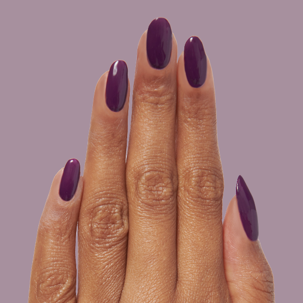Hand with Who Likes Raisins? long-lasting gel polish on almond-shaped nails against soft purple background