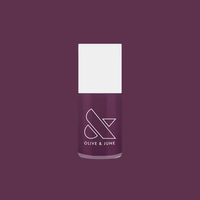Olive and June bottle of Who Likes Raisins? gel polish in dark purpley-red shade against matching purple background