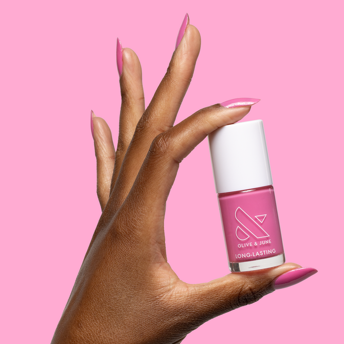 Hand holding bottle of Your Favorite Suit long-lasting gel polish with matching glossy peony pink manicure