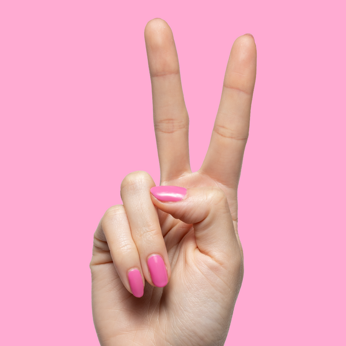 Your Favorite Suit showing hand with glossy bright peony pink gel polish manicure on two fingers against pink background