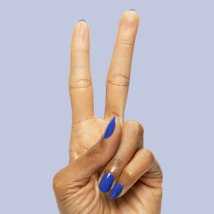 Hand showing peace sign with nails painted in bright denim blue Your Mani Looks So Good in Those Jeans polish