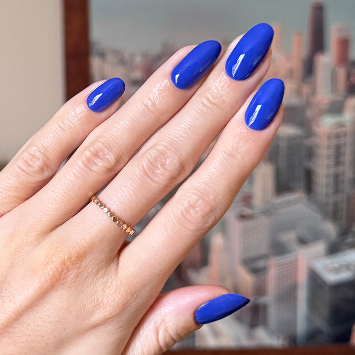 Hand with glossy bright blue gel polish Your Mani Looks So Good in Those Jeans manicure against cityscape background