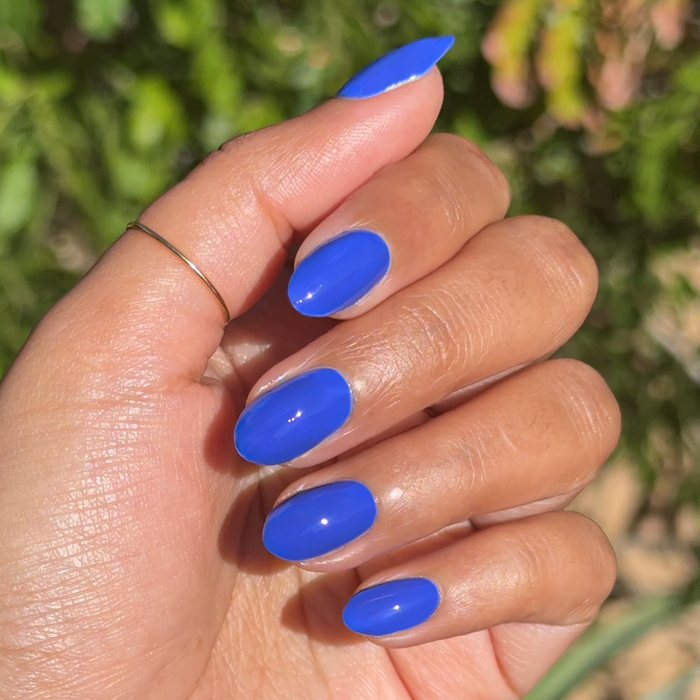 Hand with glossy bright nails painted in Your Mani Looks So Good in Those Jeans polish for a vibrant manicure look